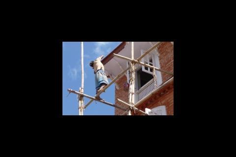 Worker balanced on scaffold poles